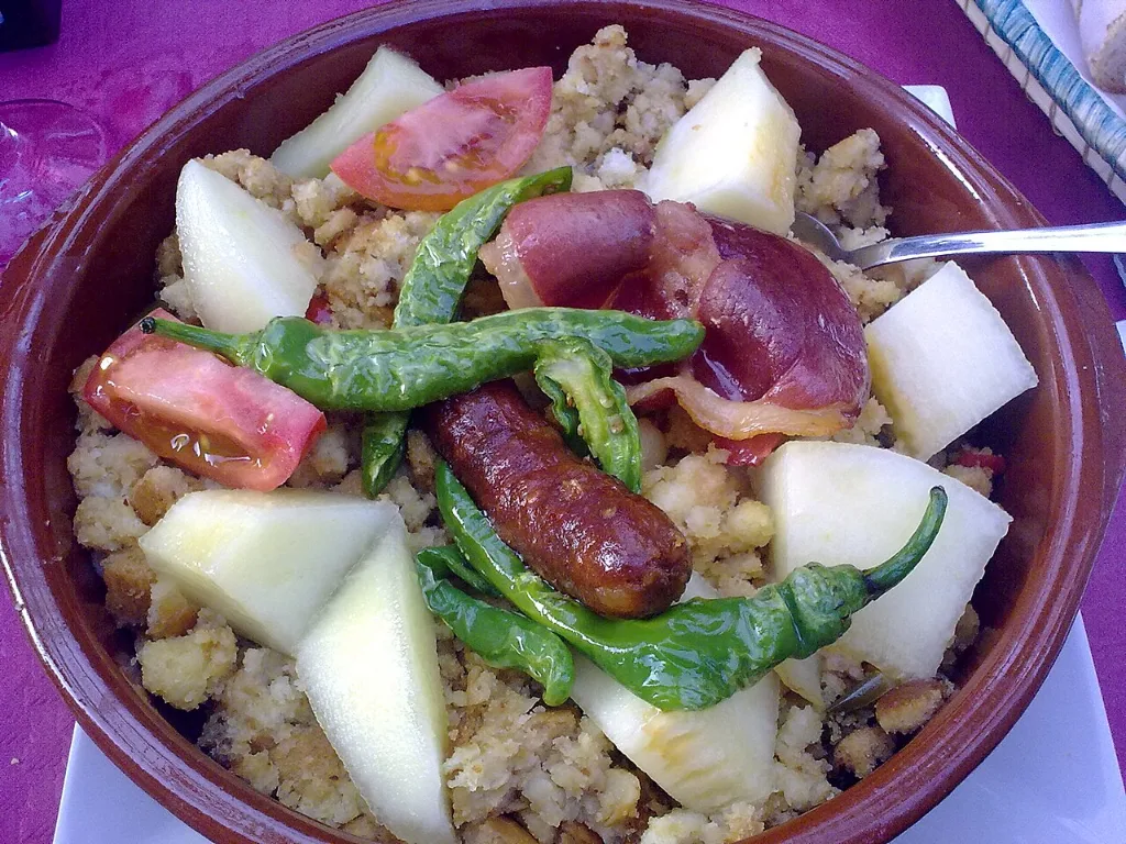 Cazuela de migas con chorizo, pimientos verdes fritos, tomate y trozos de melón