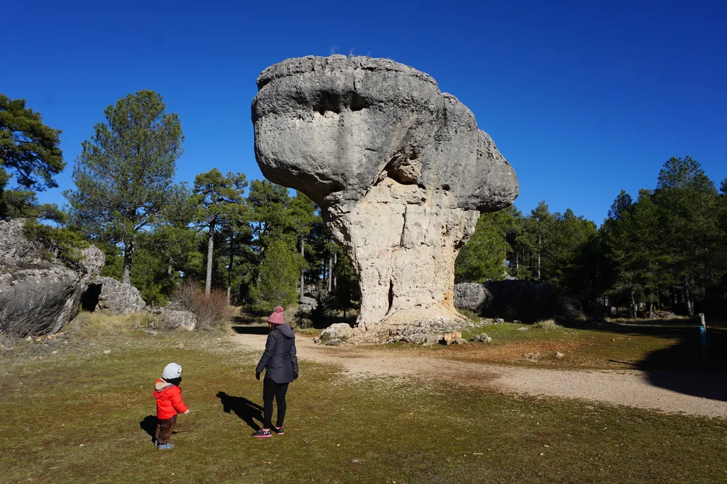 Gran roca en forma de seta en la Ciudad Encantada de Cuenca, con dos visitantes en primer plano que dan idea de su tamaño