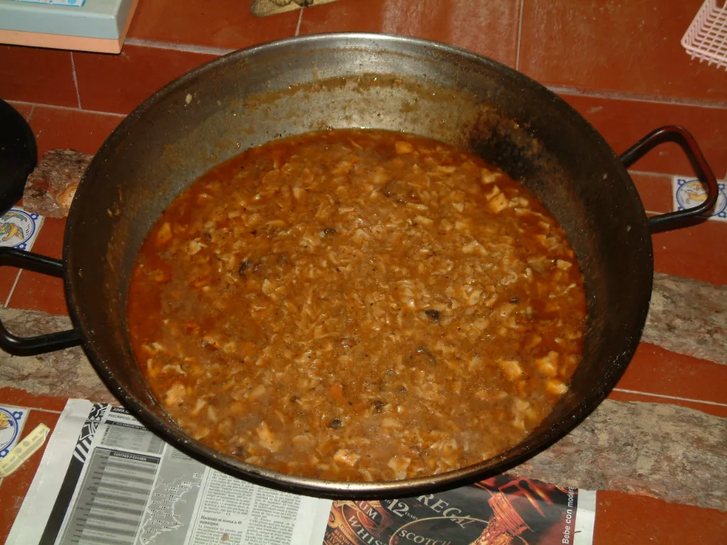 Gazpachos manchegos cocinados en una paella grande sobre el fuego