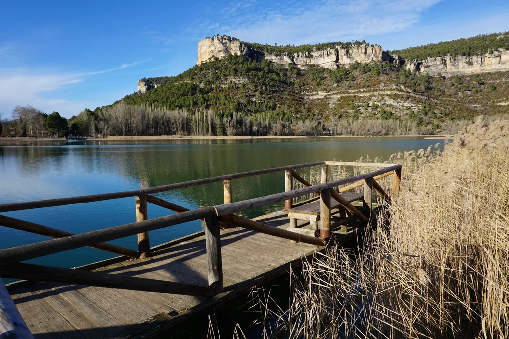 Mirador de madera sobre la laguna de Uña, con el agua en calma y los cortados de roca al fondo