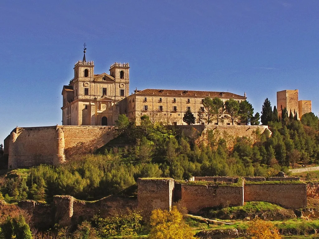 Monasterio de Uclés sobre el cerro, con sus torres y la fachada sur, rodeado de vegetación