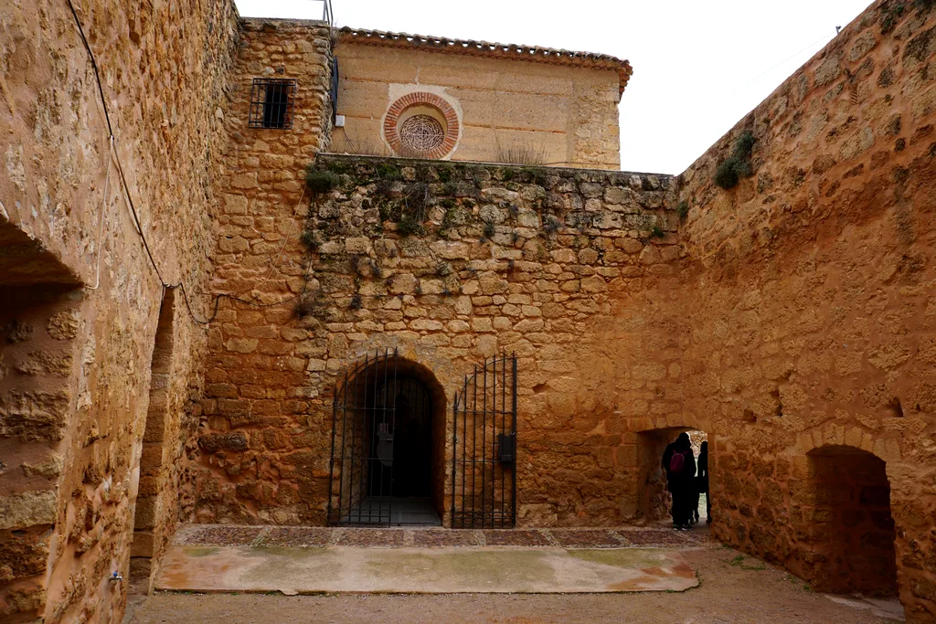 Patio de armas del castillo de Peñarroya con la puerta enrejada y el rosetón del santuario al fondo