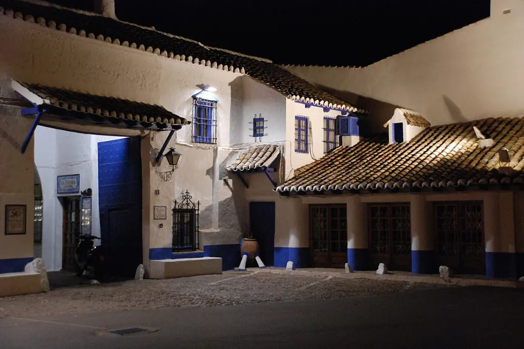 Patio encalado con soportales y galería de madera de la Venta del Quijote, en Puerto Lápice, iluminado al anochecer