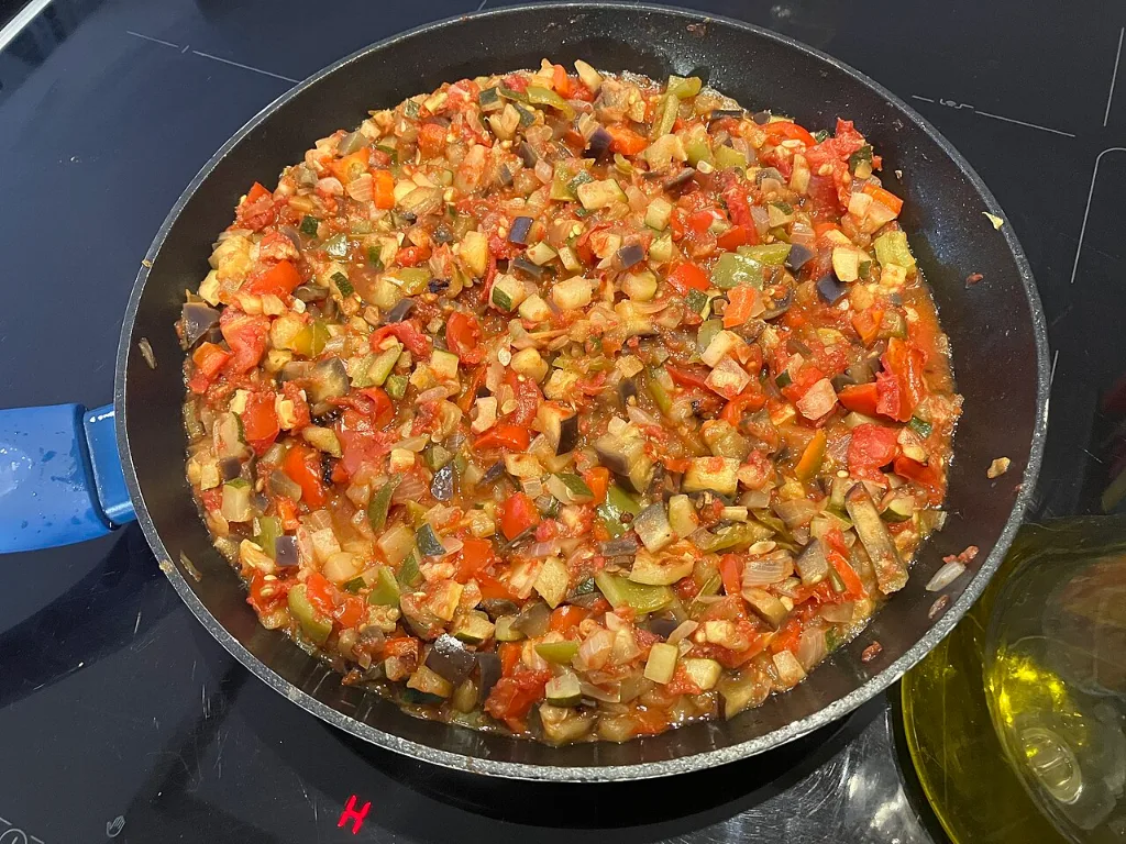Pisto manchego recién hecho en una sartén, con dados de pimiento, tomate, cebolla y calabacín