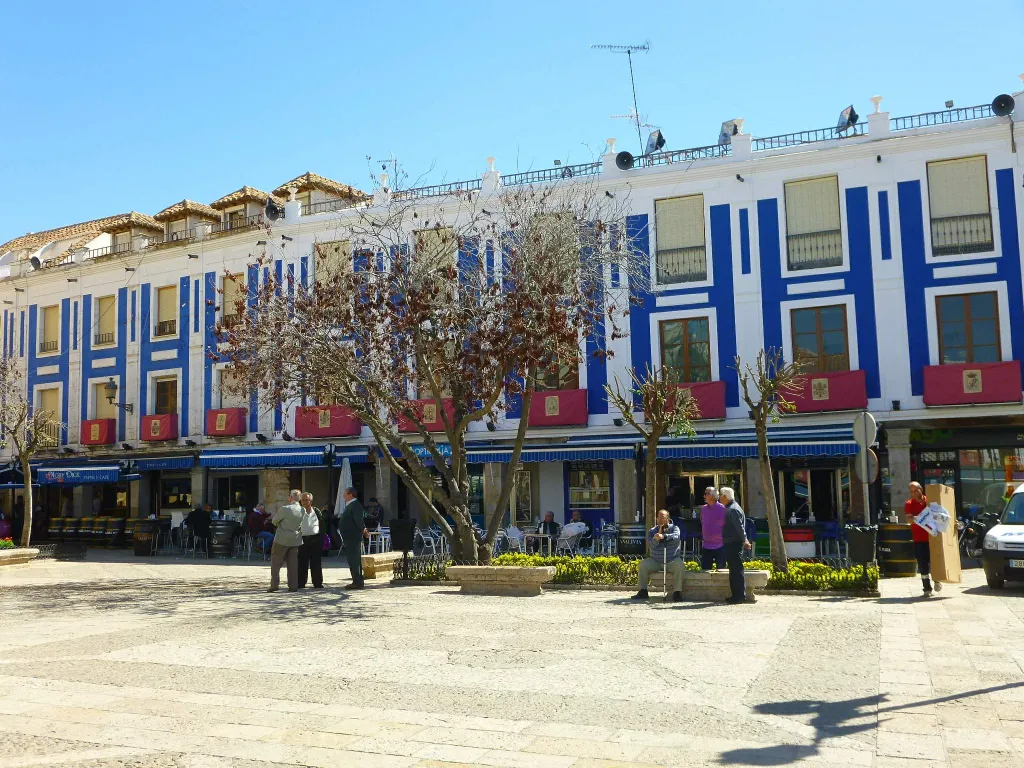 Plaza de España de Valdepeñas con sus fachadas blancas y añil y los soportales