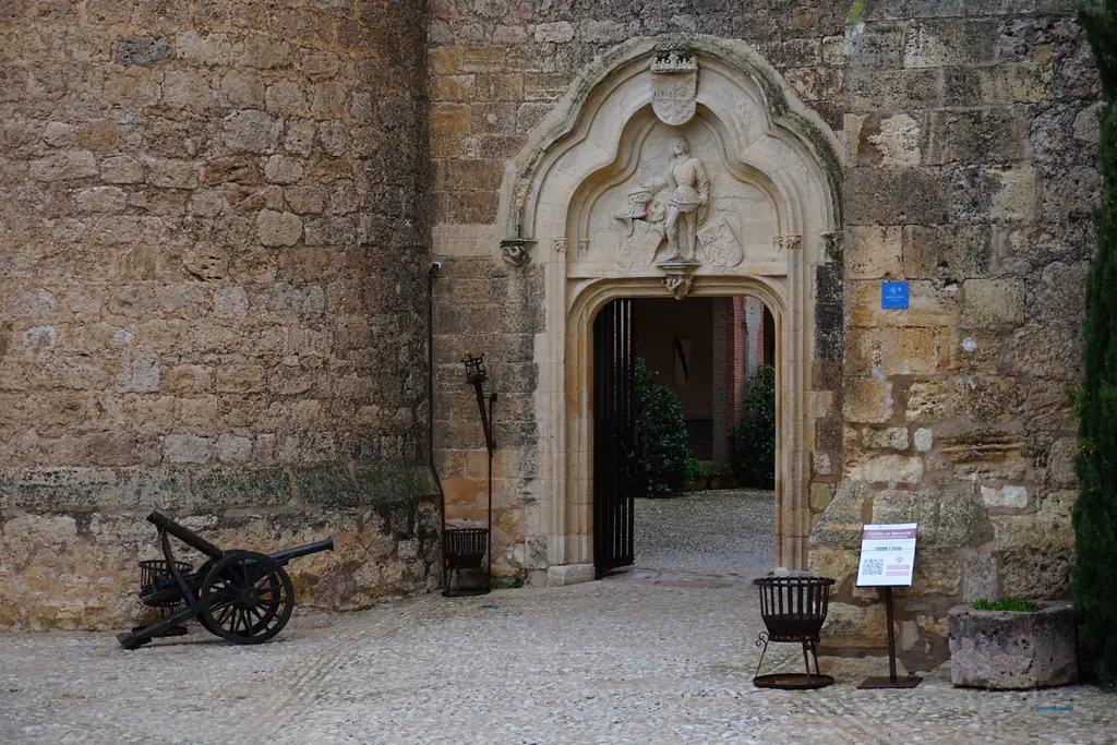 Portada gótica de acceso al patio del Castillo de Belmonte, con un cañón al lado