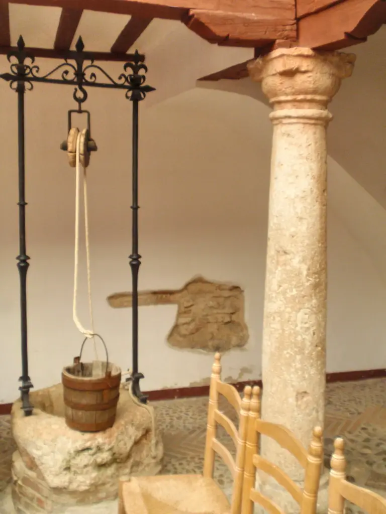 Pozo con polea y cubo de madera junto a una columna de piedra en el Corral de Comedias de Almagro