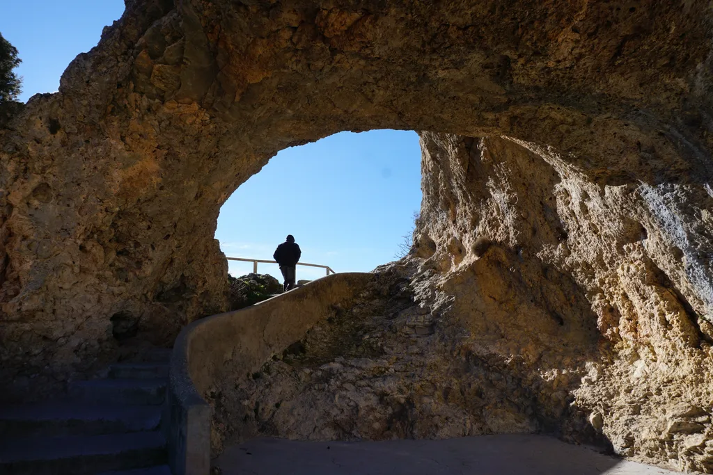 Arco de roca del Ventano del Diablo con un visitante asomado al mirador sobre el cañón